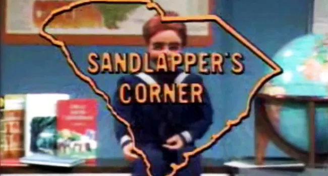 Sandlapper&#039;s Corner logo with Sammy the puppet behind it